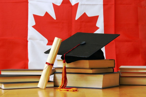 A graduation cap and diploma on top of booksDescription automatically generated
